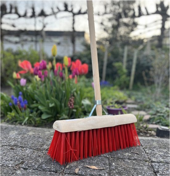 Nylon bezem op stenen ondergrond met bloemen
